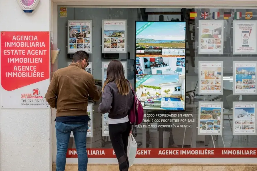 Una pareja se detiene a observar las propiedades en venta anunciadas en el escaparate de una agencia inmobiliaria, en una imagen de archivo / EFE