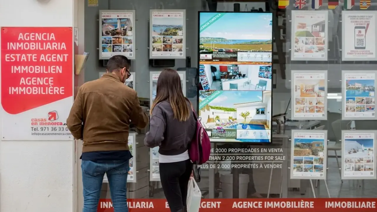 Una pareja se detiene a observar las propiedades en venta anunciadas en el escaparate de una agencia inmobiliaria, en una imagen de archivo / EFE