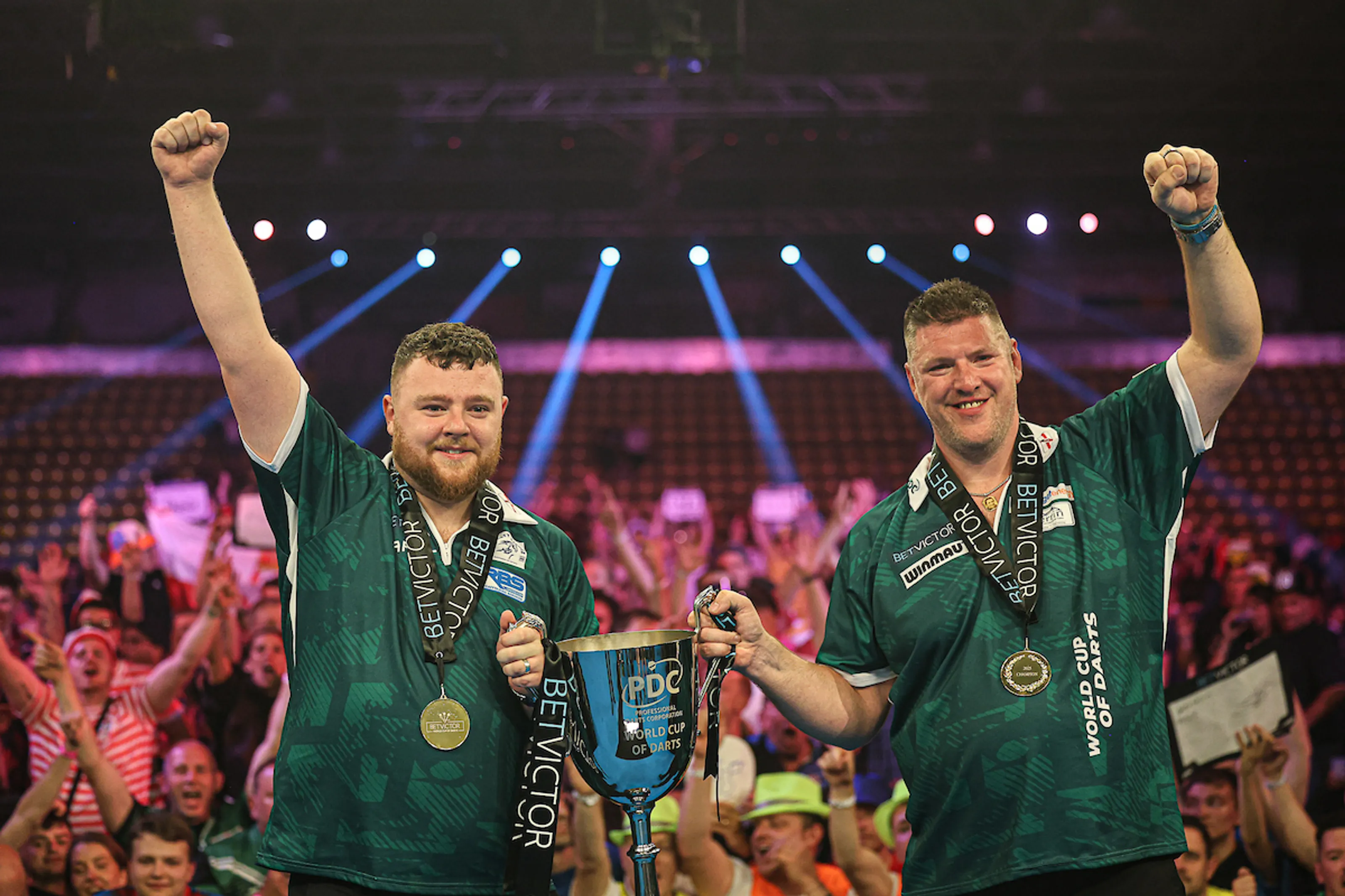 Josh Rock (izq.) y Daryl Gurney (dcha.), levantando el trofeo de la Copa del Mundo de Dardos / PDC